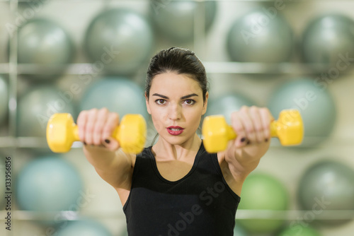 beautiful girl doing exercise with yellow dumbbell