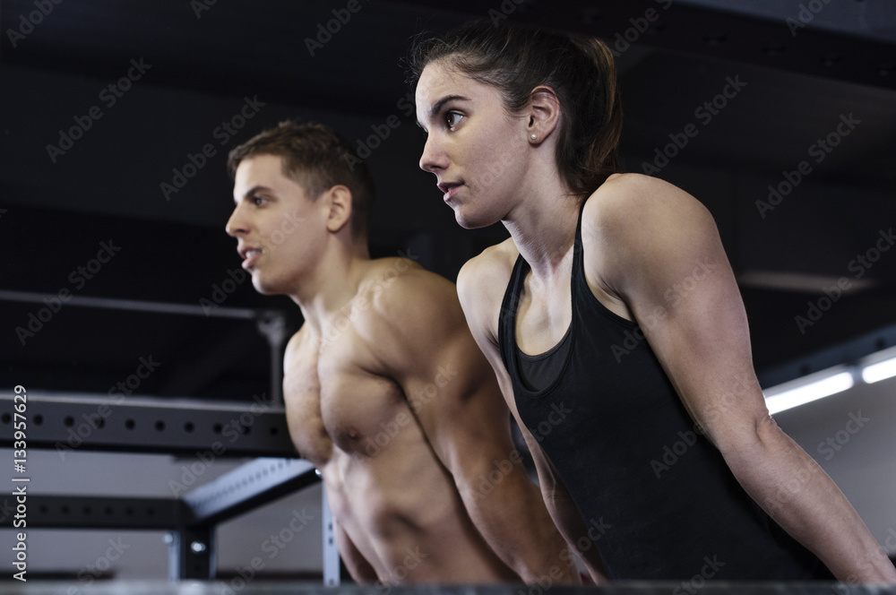 Low angle view of determined male and female athletes exercising in gym Low angle view of determined male and female athletes exercising in gym