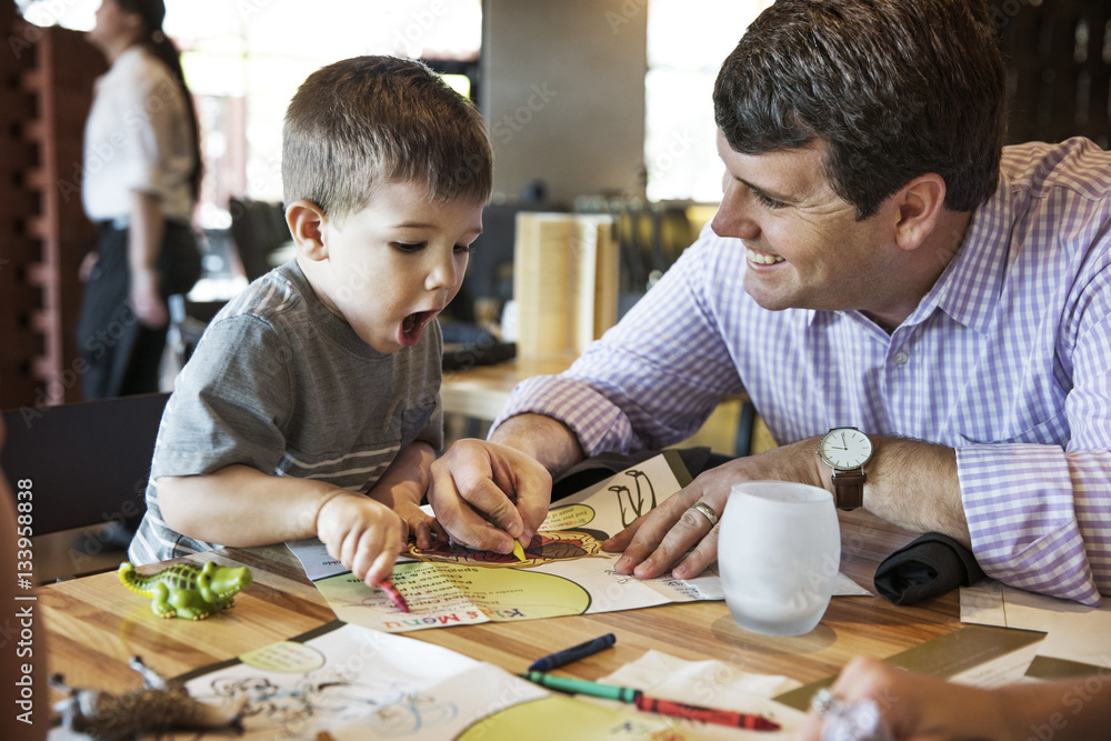 Father and son coloring menu together in the restaurant Father and son coloring menu together in the restaurant