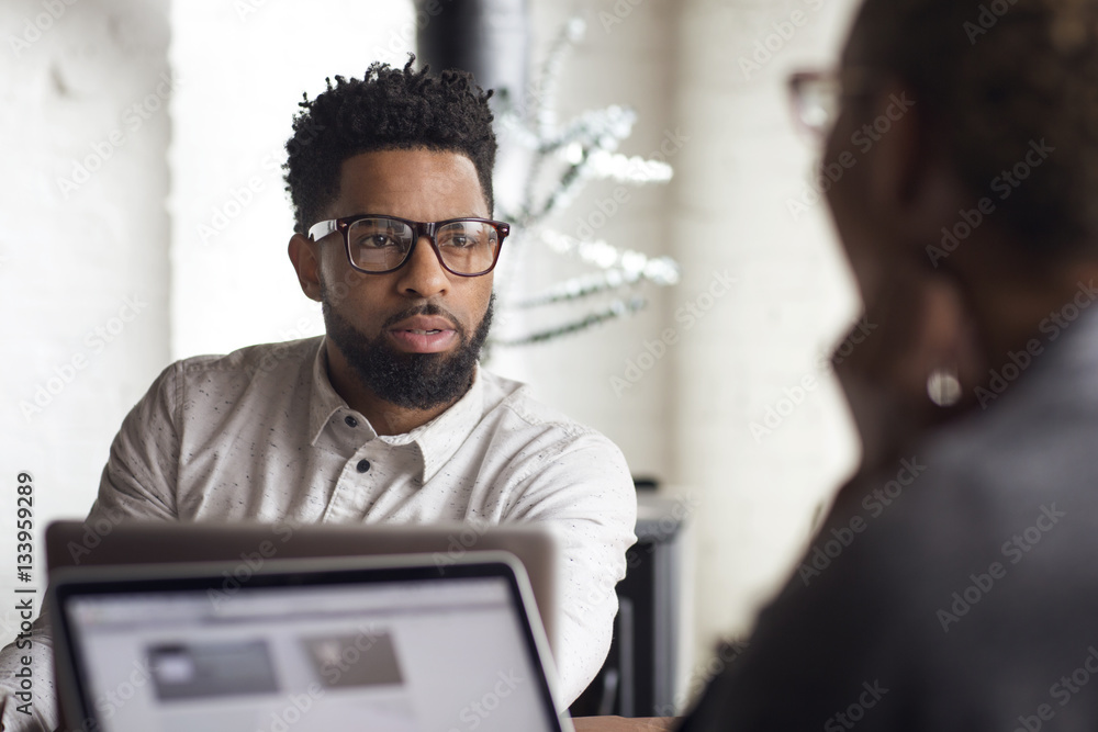 Young man talking to woman while using laptop at home Young man talking to woman while using laptop at home