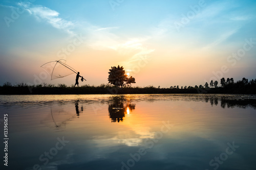 Vietnamese rural countryside sunset scene with silhouette farmers carrying bamboo fish traps home