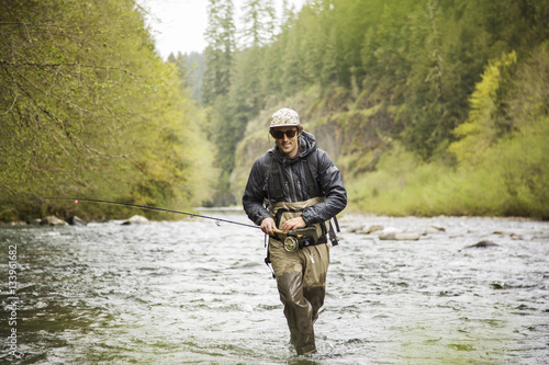 Man walking with fishing rod in river photo