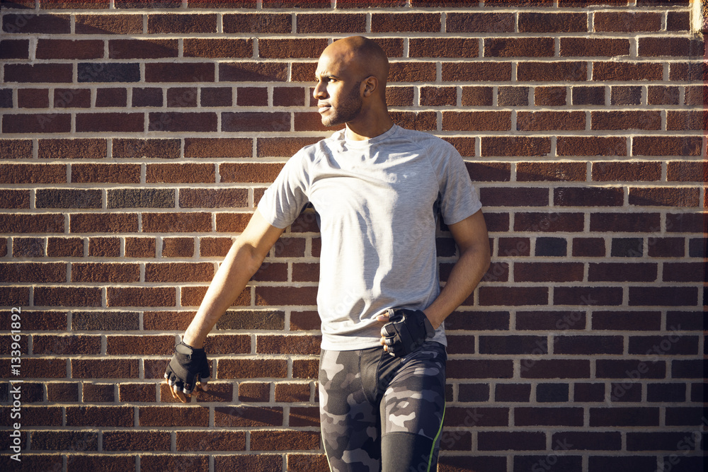 Determined male athlete standing against brick wall Determined male athlete standing against brick wall