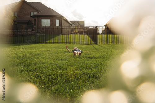 Boy relaxing on grassy field in backyard