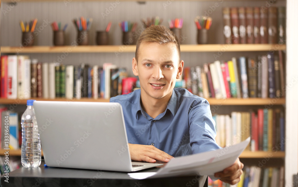 Handsome man with laptop studying in library Handsome man with laptop studying in library