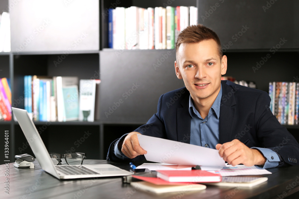 Obraz premium Handsome man with laptop studying in library