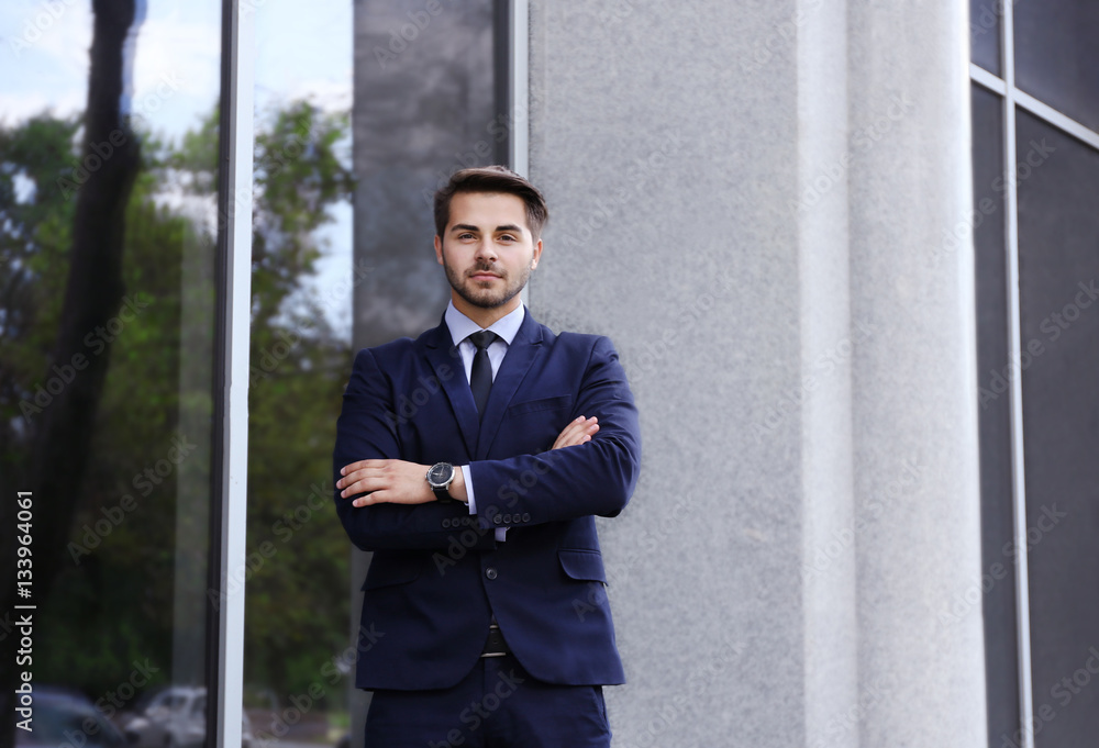 Young businessman on office building background Young businessman on office building background
