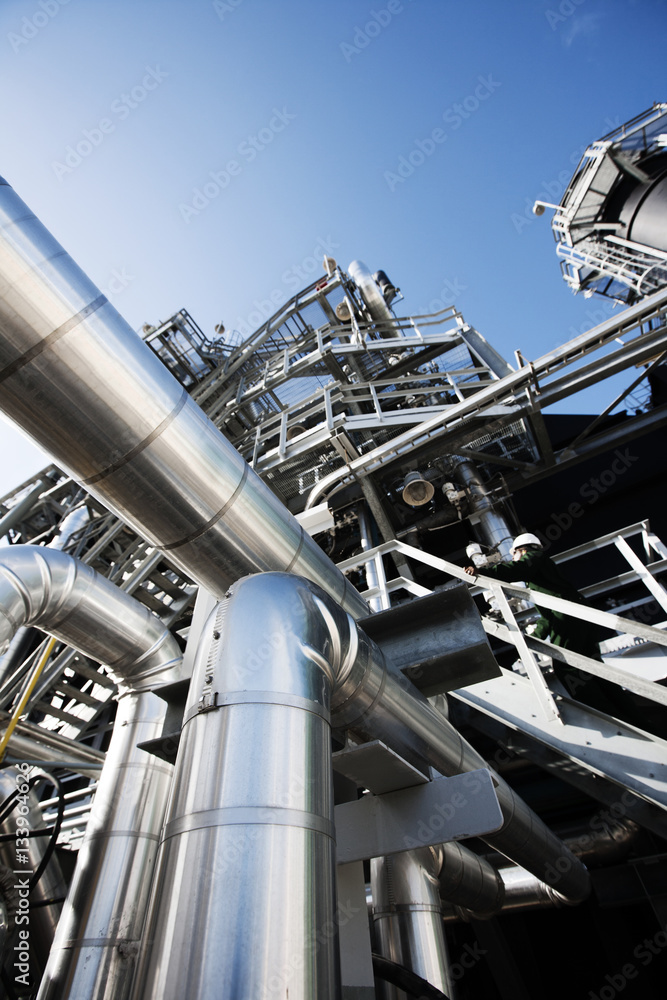 Low angle view of pipelines at industry against clear blue sky Low angle view of pipelines at industry against clear blue sky