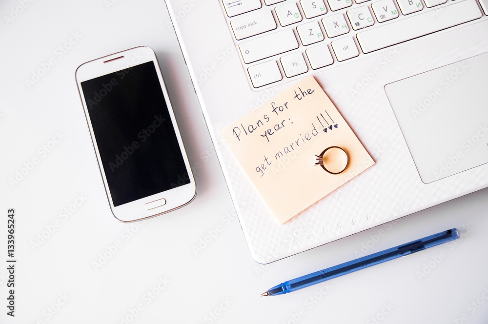 Plans for year get married with laptop, pen and cell phone on white background Plans for year get married with laptop, pen and cell phone on white background