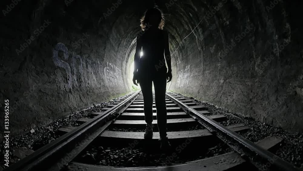 Black silhouette of woman standing in dark railway tunnel cinematic background Black silhouette of woman standing in dark railway tunnel cinematic background