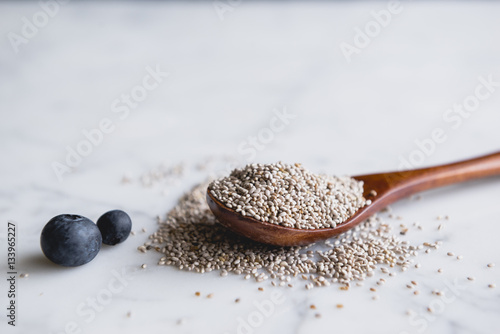 Wooden spoon with chia seeds and blueberries on marble counter photo