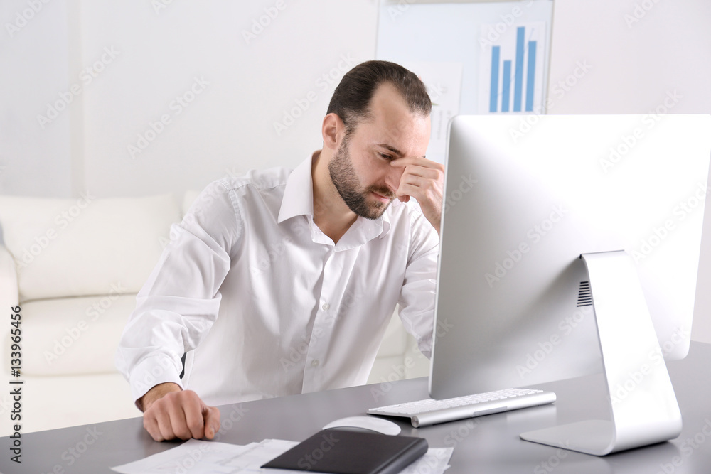 Fototapeta premium Depressed handsome man sitting in office