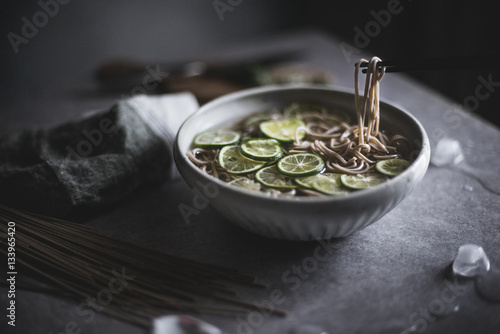 Close up of soba noodles in bowl with chopsticks on kitchen counter photo