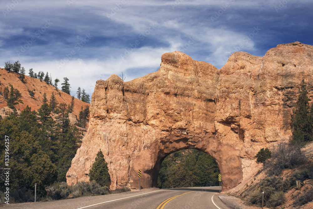 Road under natural arch against sky Road under natural arch against sky