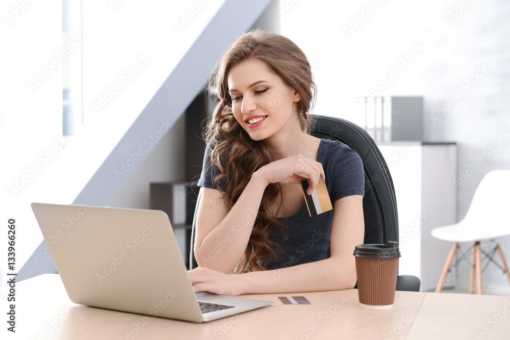 Obraz premium Young woman shopping online with credit card and laptop at home