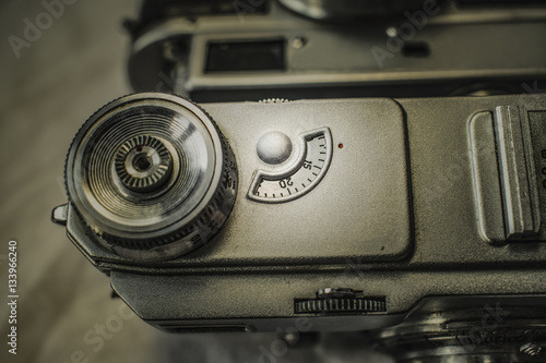 Close up view from above of old Russian analog film camera on dirty canvas with vintage look. On the camera  there can be seen shutter release and shutter speed knobs