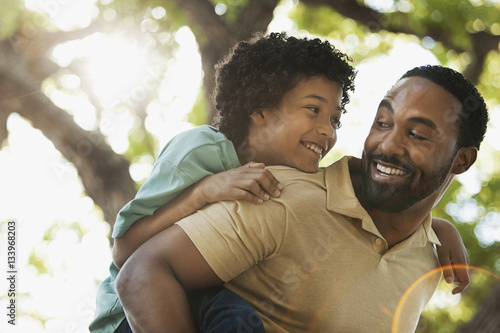 Happy father piggybacking son on sunny day photo