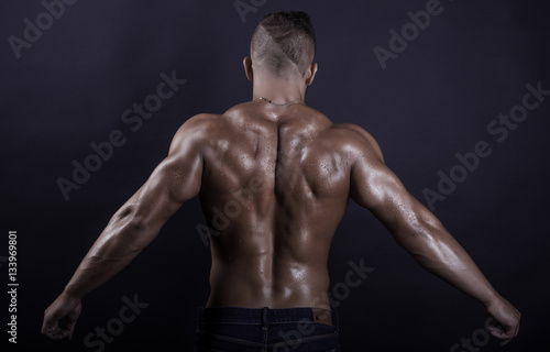 Handsome, muscular and sexy back of young man stretching arms