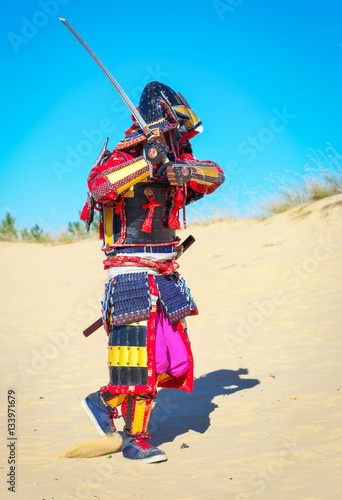 Men in samurai armour with sword running on sand