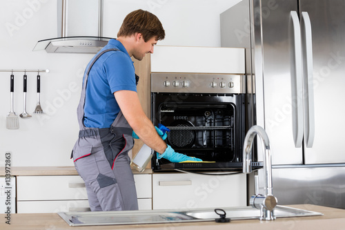 Man In Overall Cleaning Oven