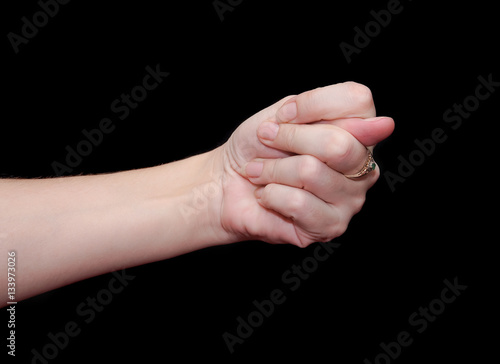 The fig sign or the combination of three fingers is an obscene gesture commonly used to deny a request. Hand isolated on black background