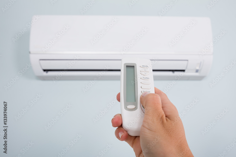 Person Operating Air Conditioner With Remote Control Person Operating Air Conditioner With Remote Control