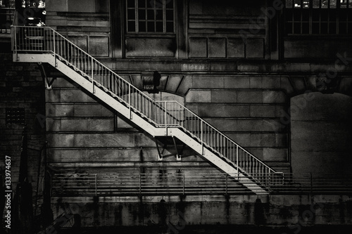 A metal staircase descends from street level down to the Chicago river along the side of a building