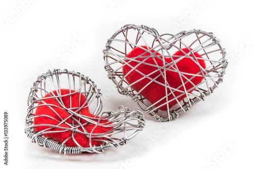 red fabric heart in knitted wire cage on white background