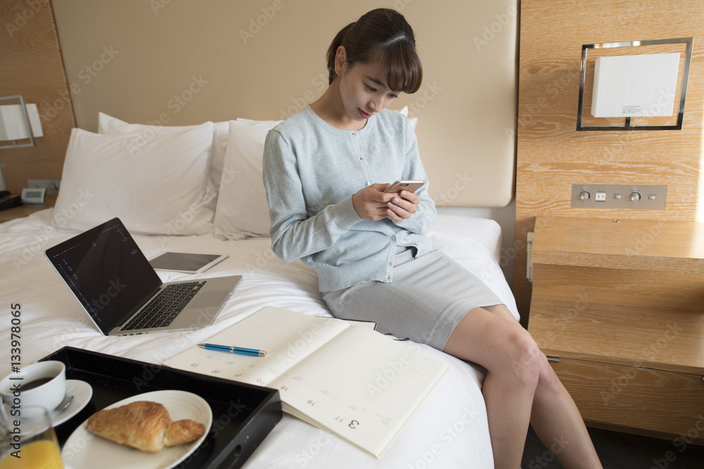 A young woman is watching a smartphone in a hotel room