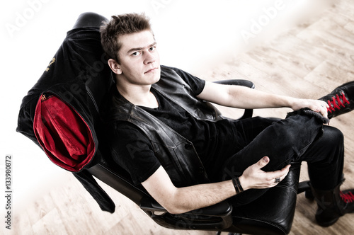 Handsome guy sits in a chair on a white background 