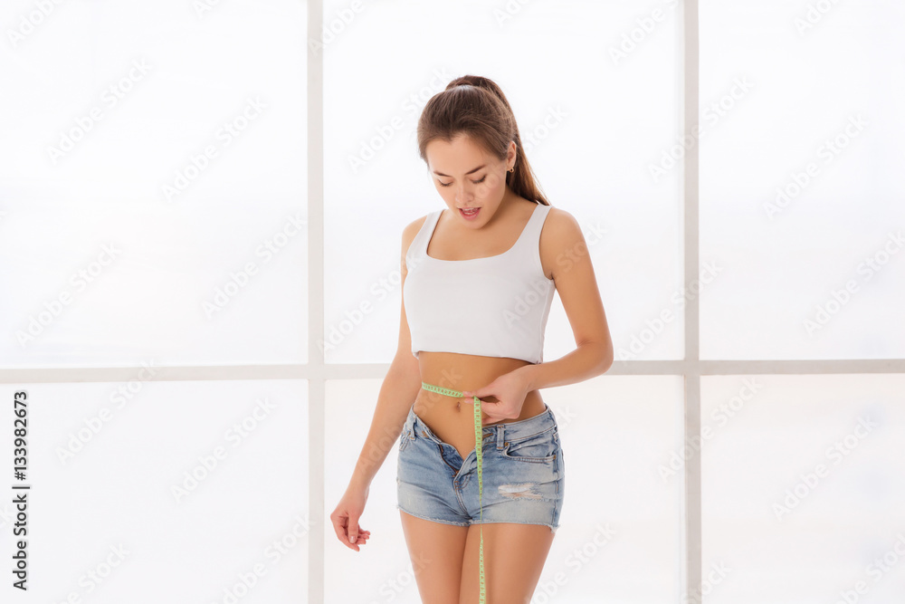 Sporty woman and measure around her body on white background
