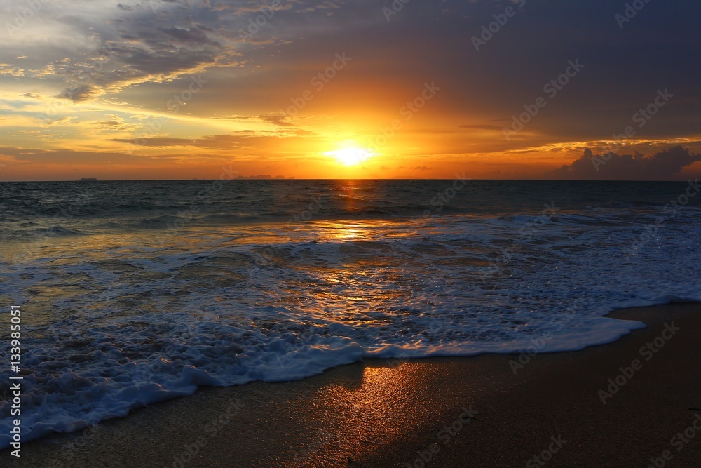 Golden sunset by the sea with soft foam wave
