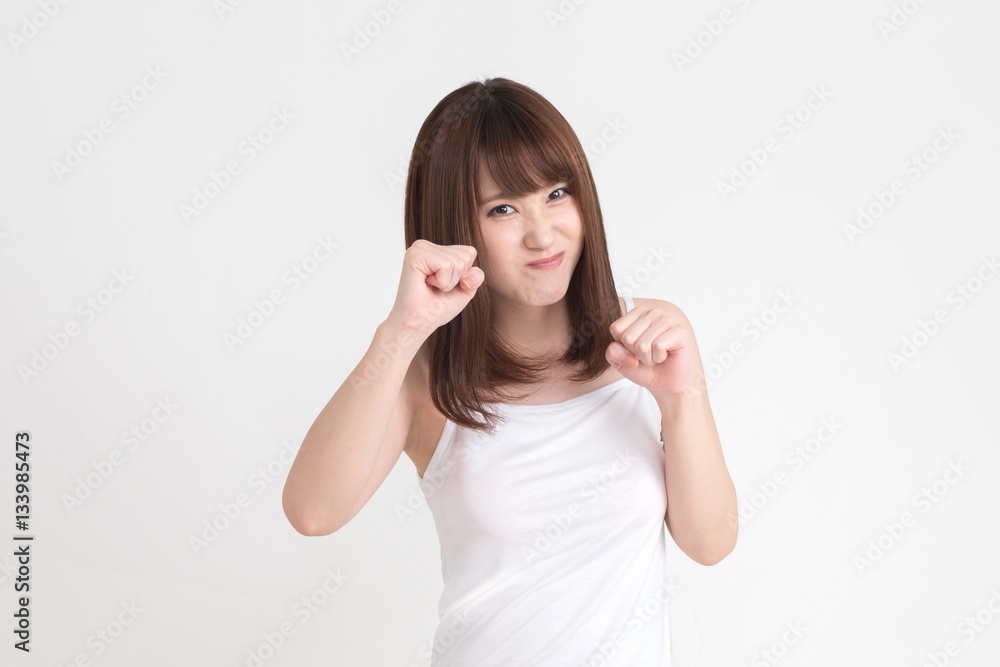 若い女性が、こぶしをふりあげて、怒りの表情をしています。 若い女性が、こぶしをふりあげて、怒りの表情をしています。