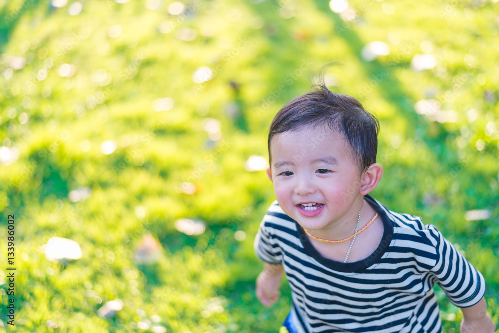 Little Asian kid playing and smiling at the playground under the Little Asian kid playing and smiling at the playground under the