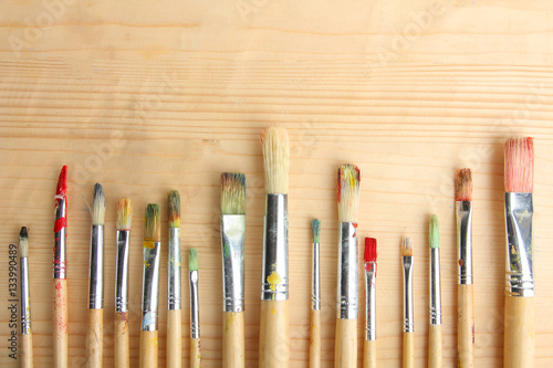 Paint brushes on a wooden background.