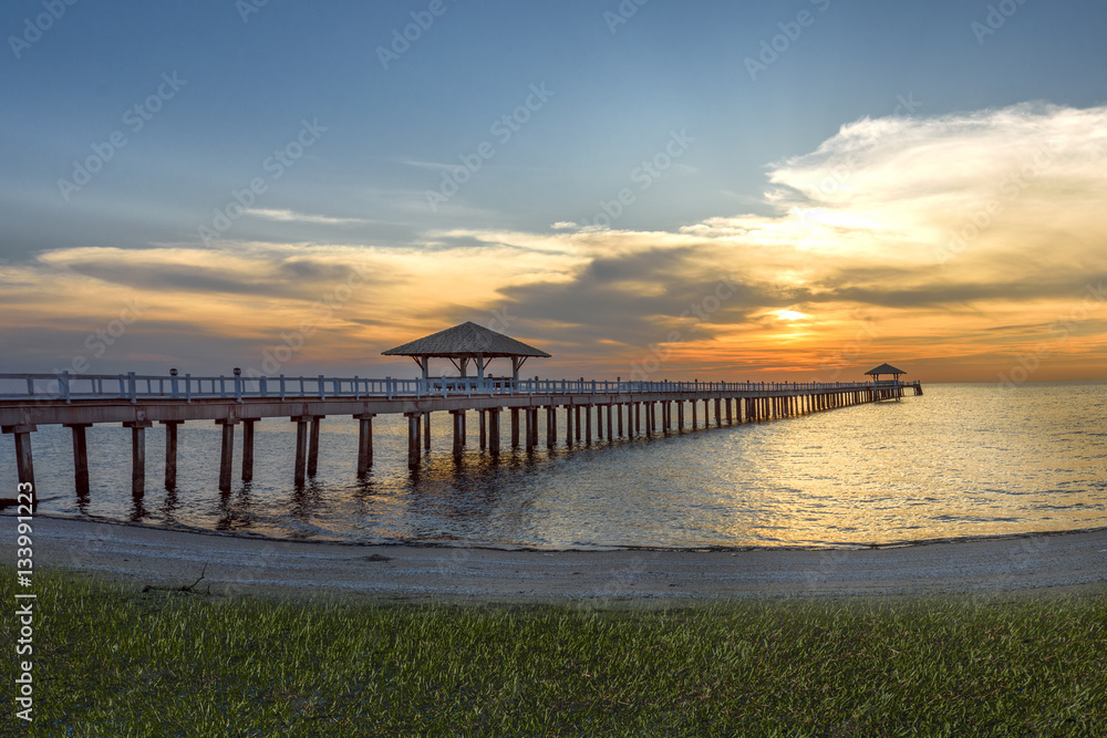 wooden bridge laying to the sea at sunset