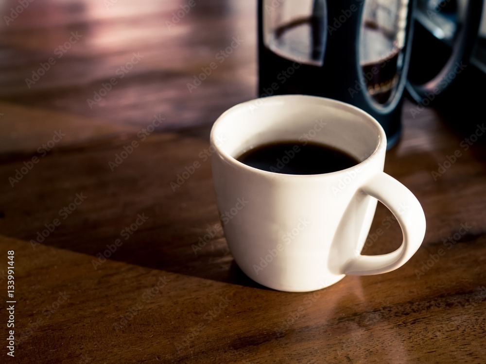 French coffee press with freshly brewed coffee, on wood table French coffee press with freshly brewed coffee, on wood table