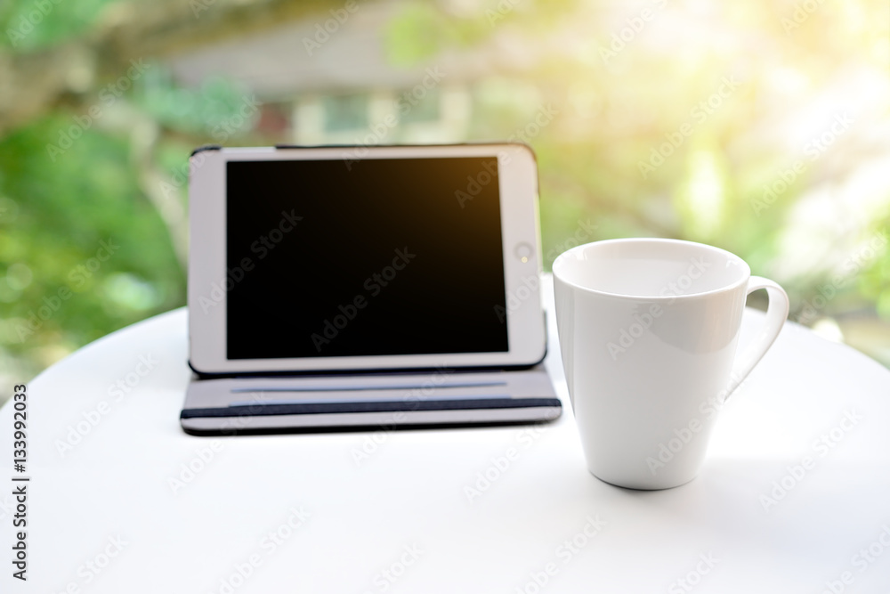 Cup of tea or coffee and tablet empty screen digital on table on