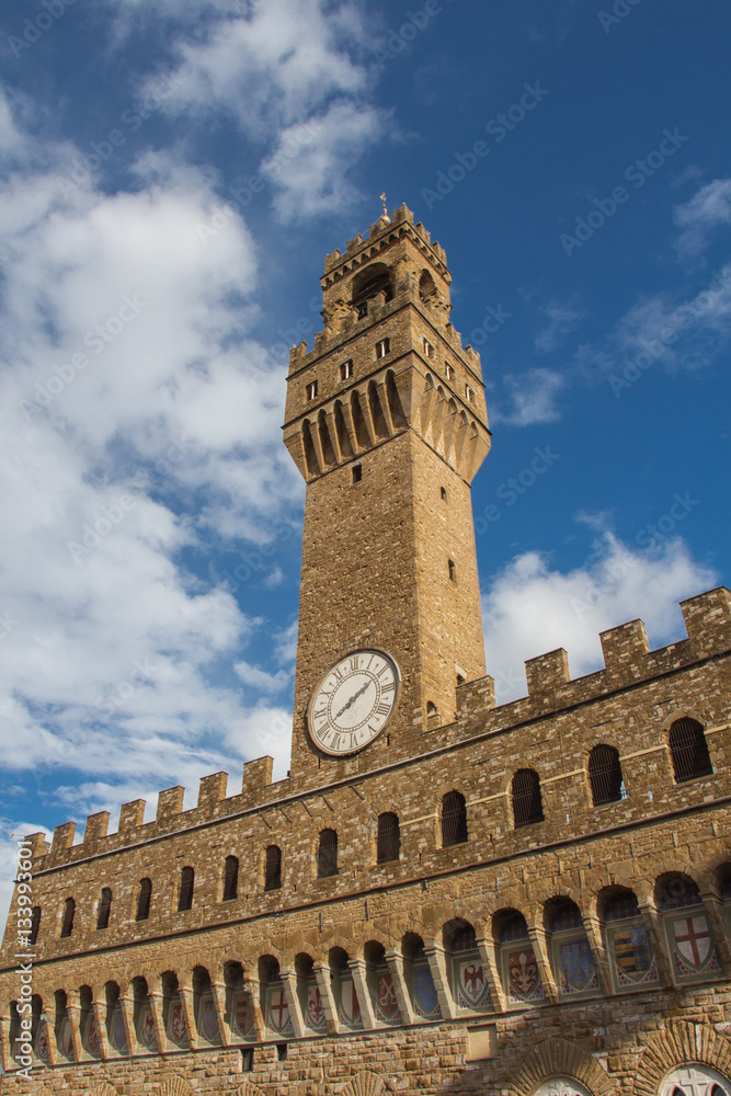 Fragment of clock tower of the Old Palace with blue sky. Tuscany. Italy.