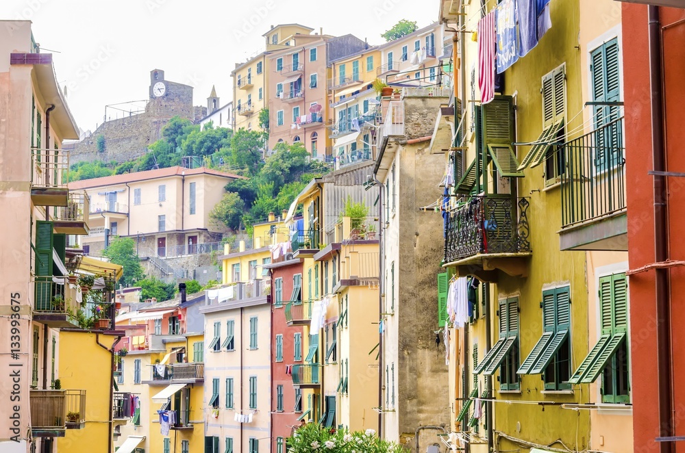 Riomaggiore village, La Spezia, Liguria, northern Italy. Colourful houses on steep hills,castle with clock,laundry on balconies.Part of the Cinque Terre National Park and a UNESCO World Heritage Site.