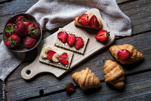 A delicious breakfast of strawberries and bread on wooden background. Fruit, food, sandwiches, cheese. Vintage style.