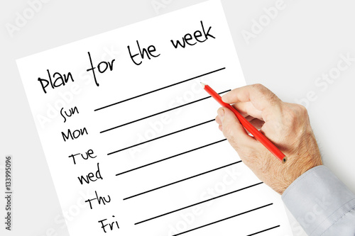 Man writes a plan for the week on the paper sheet