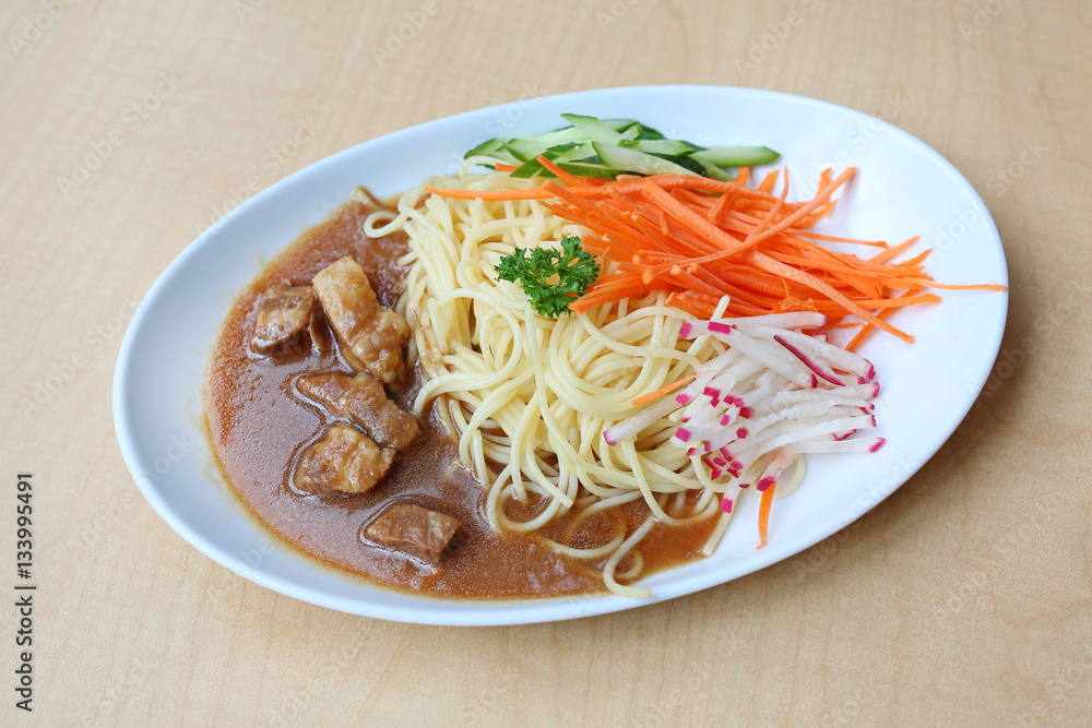 Spaghetti with steamed pork and vegetable on white plate against wooden background Spaghetti with steamed pork and vegetable on white plate against wooden background