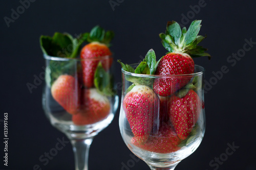 Strawberry with green leaves in vine glasses on black background