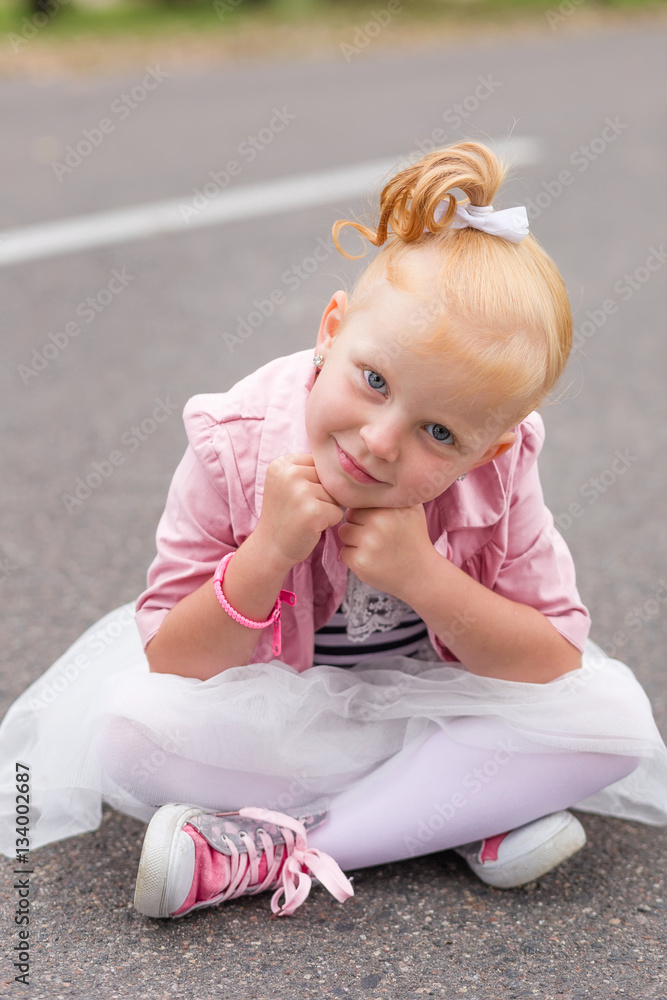 A cute little girl in a beautiful dress and sneakers playing on