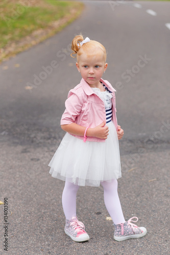 A cute little girl in a beautiful dress and sneakers playing on © Nadya Kolobova