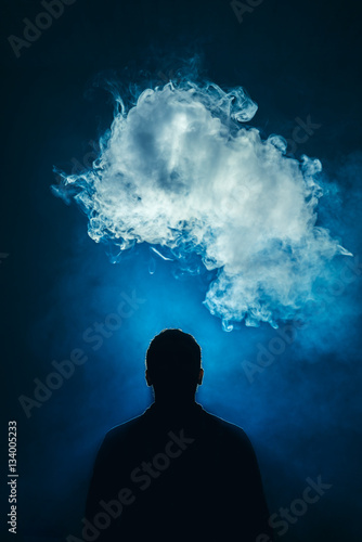 The man smoke an electric cigarette on the background of a blue light