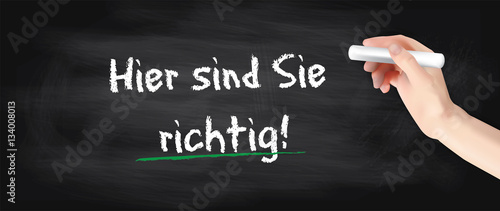 Hand schreibt auf Kreidetafel - Hier sind Sie richtig!