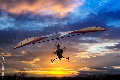 Motorized hang glider flying in the sunset