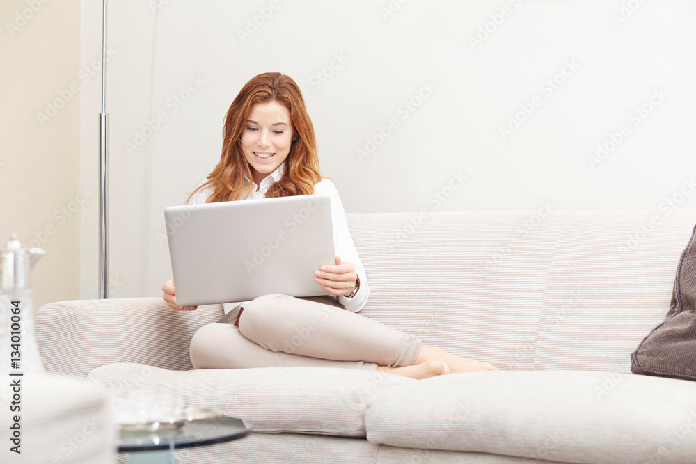 Young girl thinks about purchasing through the internet sitting on the sofa Young girl thinks about purchasing through the internet sitting on the sofa